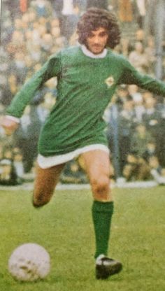 a young man kicking a soccer ball on top of a field