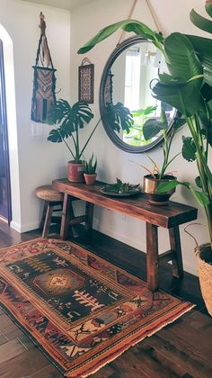 a living room with plants and rugs on the floor next to a round mirror