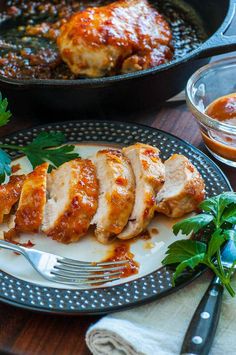 a plate with some meat and sauce on it next to a pan full of food