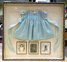 a framed photo of a baby's dress and pictures