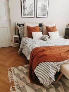 a bed sitting in a bedroom next to two pictures on the wall and a rug