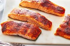 four salmon fillets on a white cutting board