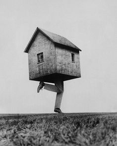 a man carrying a house on his back in the middle of an open field with grass