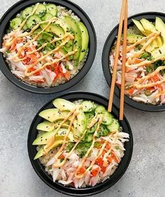 three black bowls filled with rice and veggies next to chopsticks on a table