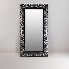 a mirror sitting on top of a table next to a white wall with a black frame