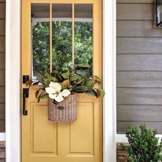 a yellow front door with a basket full of flowers