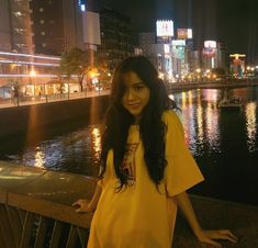 a woman standing next to a river at night