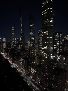 the city skyline is lit up at night, with many cars driving on the street