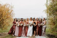 a group of women standing next to each other in front of some bushes and trees