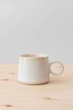 a white cup sitting on top of a wooden table