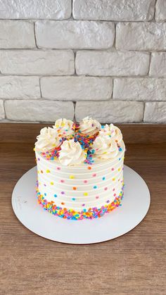 a cake with white frosting and sprinkles sitting on top of a table