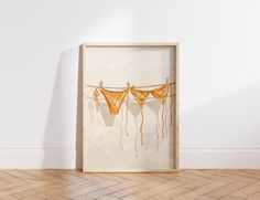 an image of clothes hanging on a line in front of a white wall and wooden floor