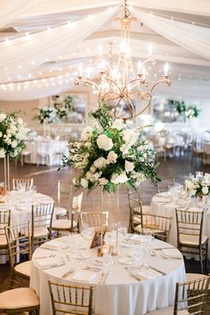 an elegant wedding reception with chandelier and white flowers on the centerpieces