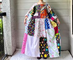 a woman standing on a porch wearing a dress made out of different fabrics and fabric