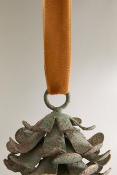 an ornament is hanging from a rope on a white background with orange ribbon