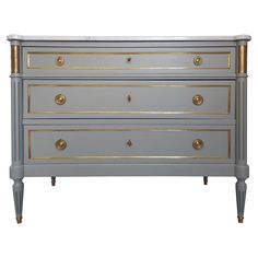 a grey dresser with gold trim and drawers