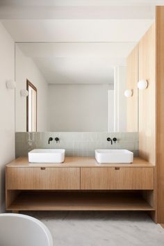 two white sinks sitting on top of a wooden counter