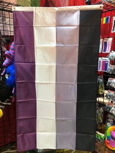 a large purple and white flag hanging on a wall in a store with other items