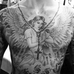 a man with tattoos on his chest holding a cross and angel wings above him is looking at the camera