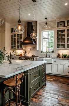 a large kitchen with an island and two pendant lights hanging from the ceiling above it