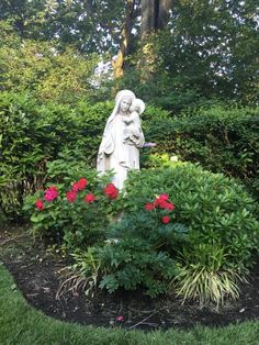 a garden with flowers and a statue in the middle