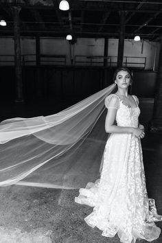 black and white photo of woman in wedding dress with veil over her head, looking at camera