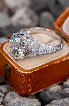 an engagement ring sitting on top of a wooden box surrounded by rocks and stones,