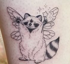 a small raccoon tattoo on the leg with wings and stars around its neck