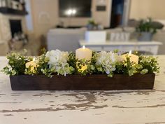 a wooden box with flowers and candles in it on top of a table next to a couch