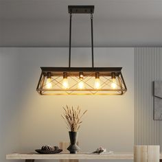 a light fixture hanging over a dining room table with flowers in vases on it