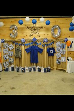 a room filled with balloons and pictures on the wall next to a wooden table covered in blue and white decorations