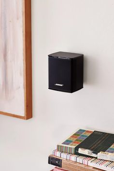 a black speaker mounted to the side of a wall next to books and a painting