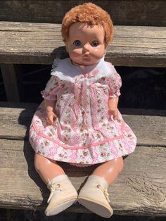 an old doll is sitting on a wooden bench