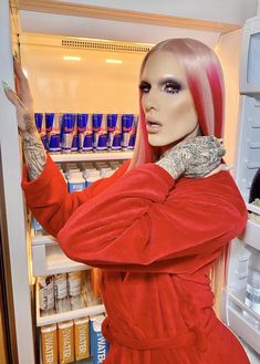 a woman with pink hair standing in front of an open refrigerator