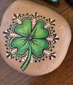 a painted rock with a four leaf clover on it, sitting on a wooden table