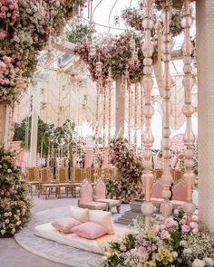 a room filled with lots of pink and white flowers next to tables covered in greenery