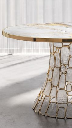 a round table with white and gold designs on the top, in an empty room