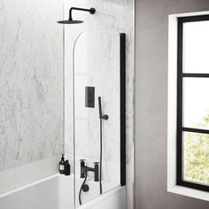 a white bath tub sitting under a window next to a sink and shower faucet