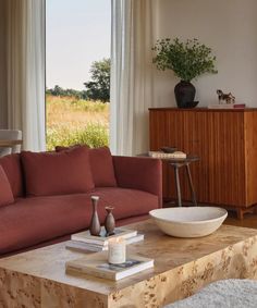 a living room filled with furniture and a bowl on top of a table in front of a window