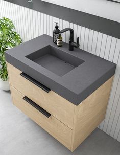 a bathroom sink sitting under a mirror next to a plant