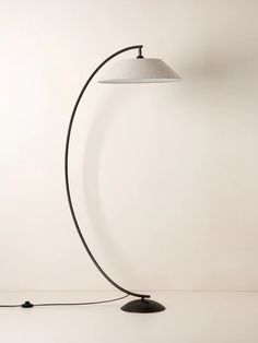 a floor lamp with a white shade on it and a black cord attached to the base