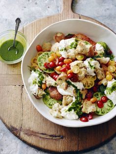 a white bowl filled with lots of food on top of a wooden table