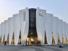 people are standing outside the entrance to a large building with white walls and arches on it