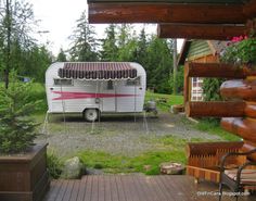 an rv is parked in the yard next to a deck with chairs and a table