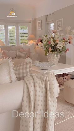 a living room with white furniture and flowers in a vase on the coffee table next to the couch