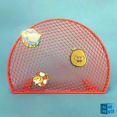 an orange mesh holder with two cartoon pin badges on the front and back of it