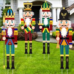 four wooden nutcrackers are standing in front of a house with green grass