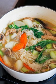 a white bowl filled with soup and vegetables on top of a black stove burner