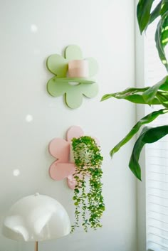 two green plants are hanging on the wall next to a lamp and a planter