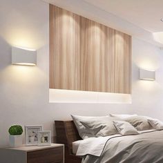 a bed sitting under two lights in a bedroom next to a wall mounted light fixture